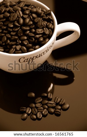 Cup of coffee & java beans close-up over black background