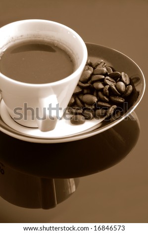 Cup of espresso coffee & Java beans over reflective black background