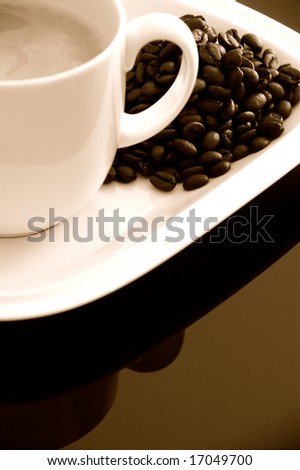 Cup of coffee & java beans close-up over reflective background