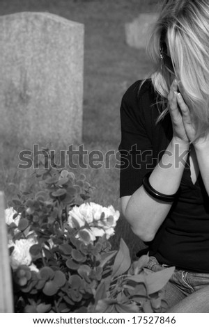Distraught woman praying at grave in black & white