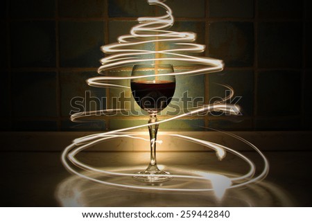Circles of light around glass of red wine, with background lit by warm temperature color.