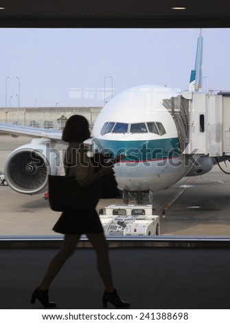 Osaka, Japan - Nov 7: Silhouette of a businesswoman boarding a Cathay Pacific passenger airplane in the Kansai International Airport in Osaka, Japan on Nov 7, 2014.