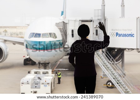 Osaka, Japan - Nov 7: Silhouette of a woman waving goodbye to a Cathay Pacific passenger airplane in the Kansai International Airport in Osaka, Japan on Nov 7, 2014.