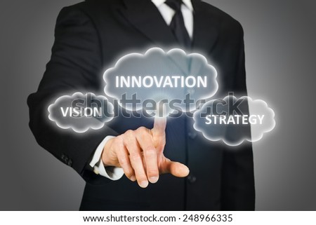 Businessman clicking on thought bubbles on a virtual touchscreen with the words innovation, vision and strategy