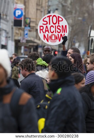 Melbourne, Australia - Jul 25, 2015: Protester holding a stop racism now placard in the crowd outside Flinders Street Station in Melbourne, Australia
