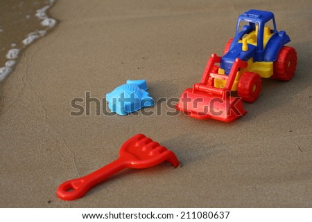 toy tractor on the sand beach summer vacation wheel rake bucket plastic fish