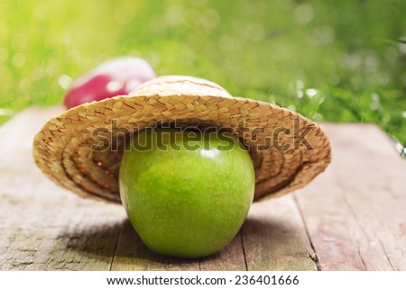 apple in a straw hat summer wooden background is an old rustic retro vintage organic product selective soft focus toned photo