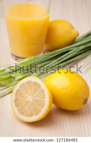 half and whole lemon with glass of juice on wooden table
