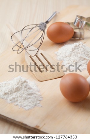 eggs, flour, cookie mold and whisk on wooden board together