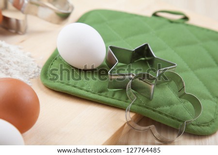 two silver cookie mold with white egg on wooden table and green napkin
