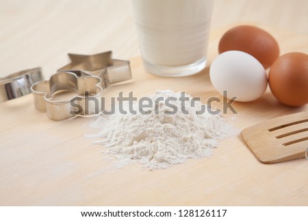 flour, glass of milk, whisk, Cookie cutter forms and eggs on wooden table together