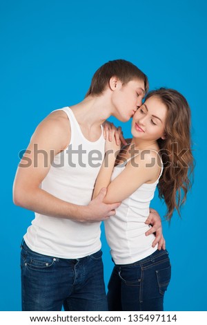 young love couple kissing and holding each other in the studio over blue background