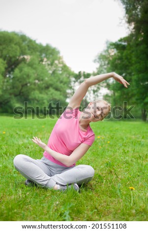 blonde girl outdoor in the park wearing grey shoes and pick t-shirt. yoga