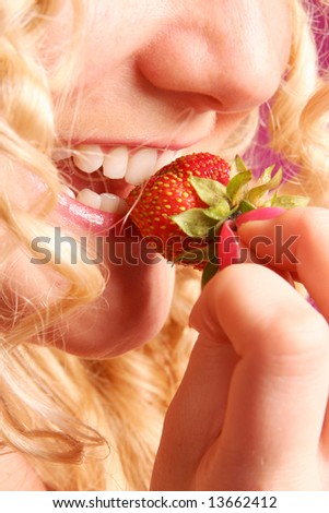 blonde curly girl biting strawberry
