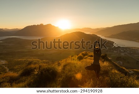 Woman practicing yoda silhouette at sunset on the mountain. New Zealand