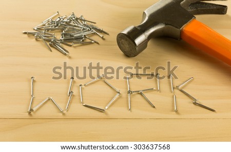 nails arranged in word WORK on wood table