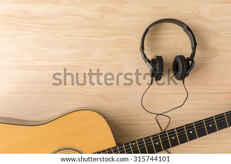 Acoustic guitar and headphone on wooden background