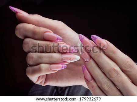 long purple nails and hands isolated on black background