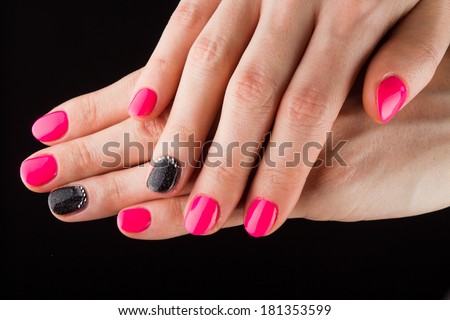 Painted pink black nails and hands isolated on black background