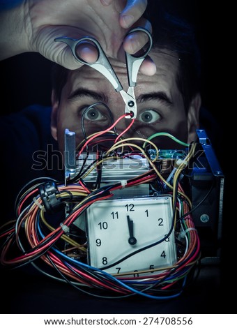 Disarming the bomb: Side cutter cutting the red wire. Isolated on the black background. items: alarm clock, nail clipper for dog, power supply, oily water on face and hand