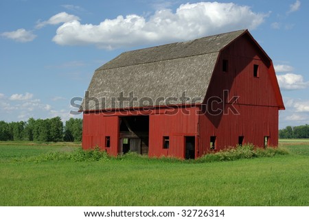 red barn alone in field with clouds in the sky