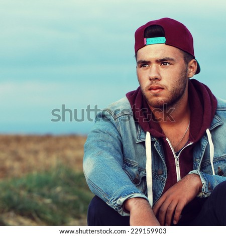 handsome hipster man thinks at nature background in field