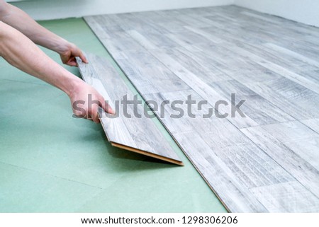 Close up of male hands installing new laminated flooring in room