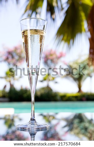 Glass of champagne on the glass table in outdoor resort bar