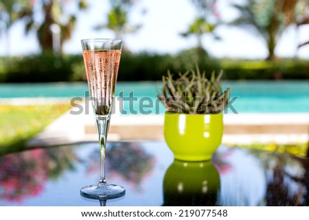 Glass of champagne on the glass table in outdoor resort bar
