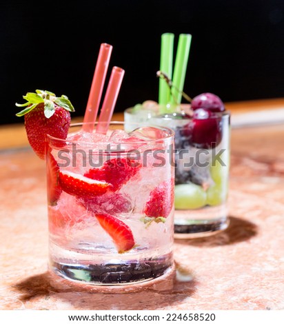 Two glasses of strawberry and grape mojitoes on marble table