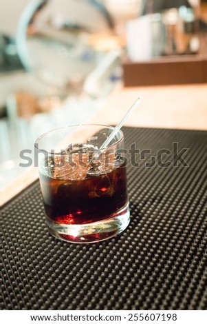 Black russian cocktail on the bar stand on rubber mat. Shallow DOF