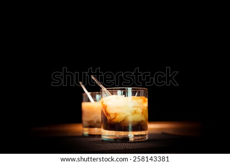 Two white russian cocktails on the bar stand on rubber mat. Shallow DOF and marsala tonned