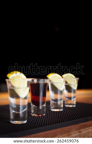 Brandy and  three tequila shots with lemon on a bar ribber mat. Shallow DOF and toned