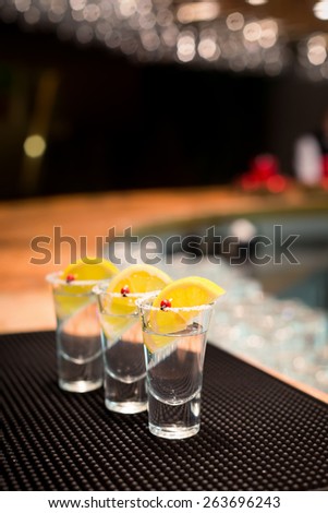 Three tequila shots with lemon on f bar ribber mat. Shallow DOF and toned