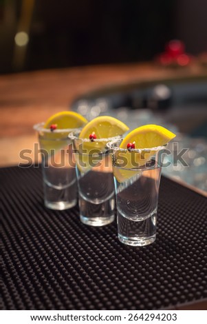 Three tequila shots with lemon on f bar ribber mat. Shallow DOF and toned