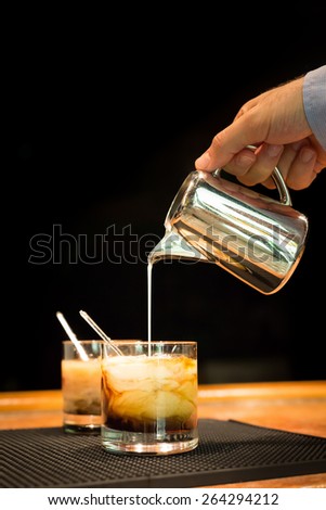 Preparation of white russian cocktails on the bar counter on rubber mat. Shallow DOF and marsala tonned