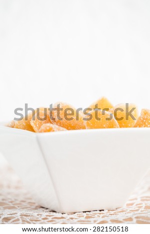 Crystallized ginger root  in white porcelain bowl. Bowl is cut vertically. Shallow DOF. Close-up photo, vertical