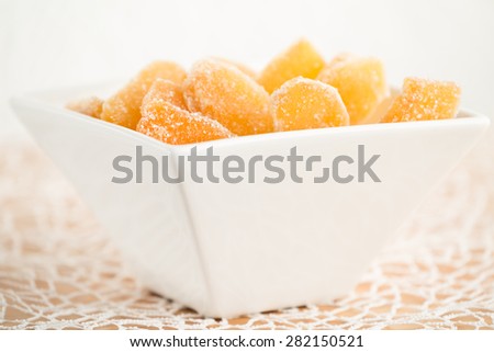 Crystallized ginger root  in white porcelain bowl. Bowl is cut vertically. Shallow DOF. Close-up photo, horizontal