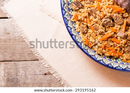Pilaf in the handmade plate on the wooden background. Horizontal