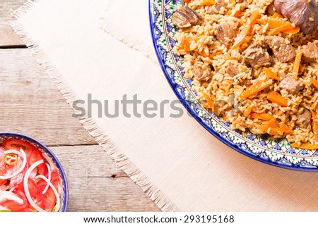 Pilaf and achichuk salad in handmade plate on wooden background. Horizontal, top view