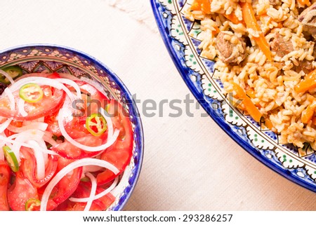 Pilaf and achichuk salad in handmade plate on wooden background. Horizontal, top view, close up