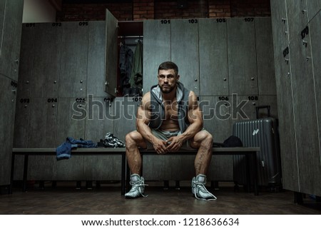 handsome muscular athletic man with a towel in the locker room after working out
