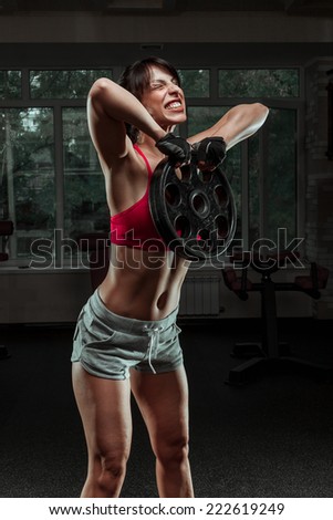 Fitness woman swinging kettle bell at gym. Young caucasian woman doing swing exercise with a kettlebell as a routine of a crossfit workout.