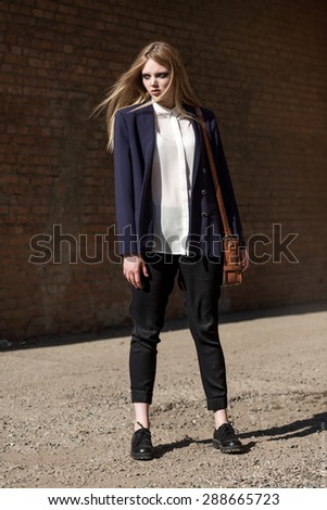 Beautiful fashion model on the street in trousers and a white shirt
