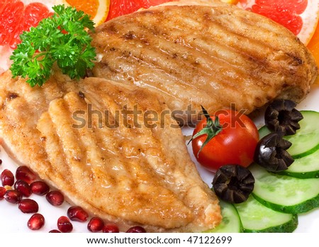 Chicken cutlets with a cucumber and a grapefruit on plate