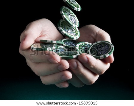 Several green twenty five valued chips falling on a pair of hands isolated over a black background.
