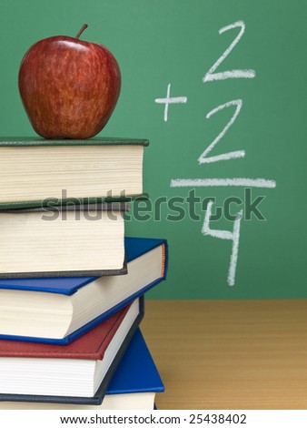 An addition on the chalkboard with an apple on top of a pile of books.
