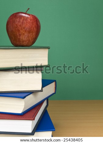 A blank chalkboard with an apple on top of a pile of books.