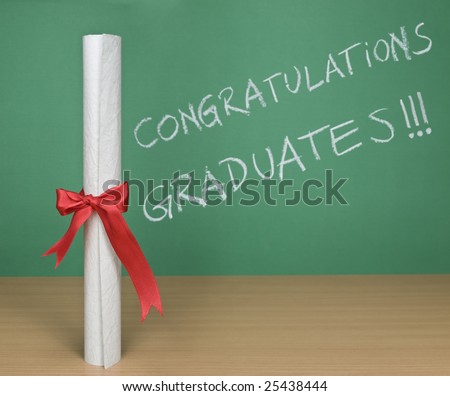 Congratulations graduates written on a chalkboard with a diploma on forefround.