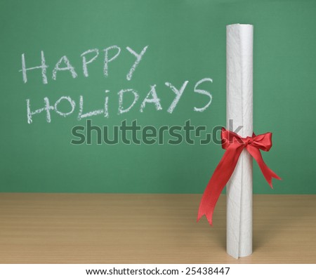 Happy holidays written on a chalkboard with a diploma on forefround.